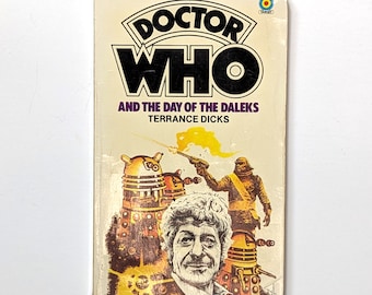 May include: A Doctor Who paperback book cover featuring a yellow and orange illustration of a Dalek, a human character, and the text "Doctor Who and the Day of the Daleks, Terrance Dicks".