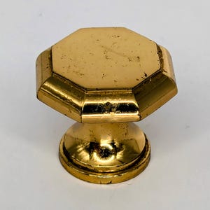 May include: A gold-toned octagonal cabinet knob with a rounded base.