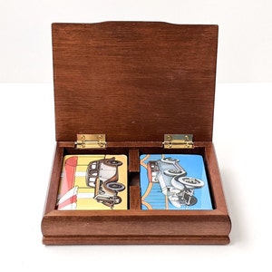 Caja de naipes de coche antiguo de mediados de siglo, teñida en teca con diseño metálico, sin usar, incluye dos barajas de cartas sin abrir.