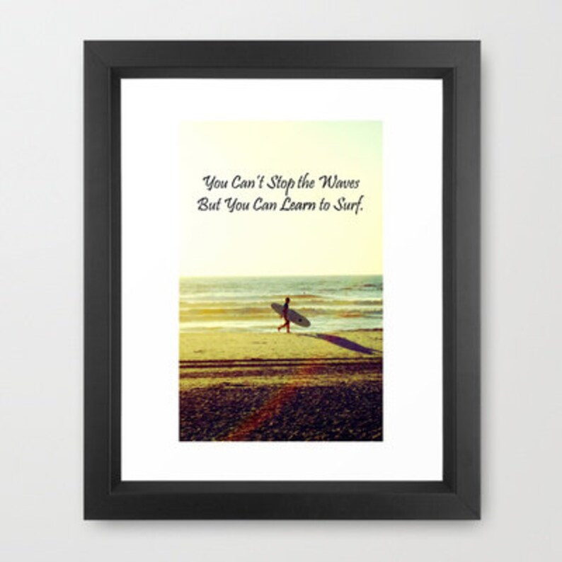 K&ouml;nnte beinhalten: Gerahmter Druck mit einer Strandszene und einer Person, die ein Surfbrett zum Meer tr&auml;gt. Der Text "You Can't Stop the Waves But You Can Learn to Surf" ist oben zu sehen. Das Bild hat eine warme, sonnige Farbpalette.