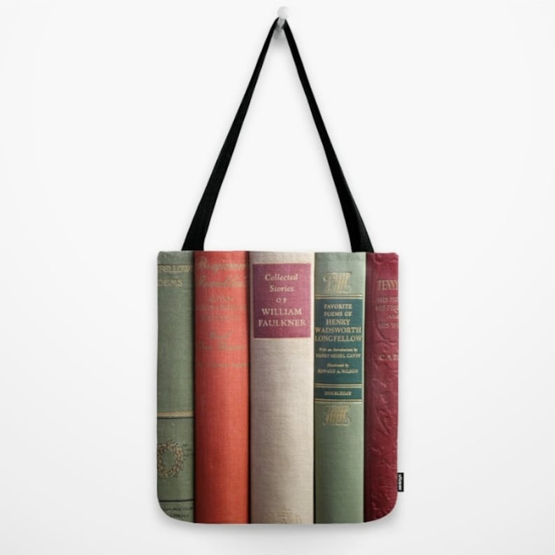 May include: A tote bag featuring a row of vintage book spines in shades of green, red, and cream. The books have gold lettering and include titles like "Collected Stories of William Faulkner" and "Favorite Poems of Henry Wadsworth Longfellow."
