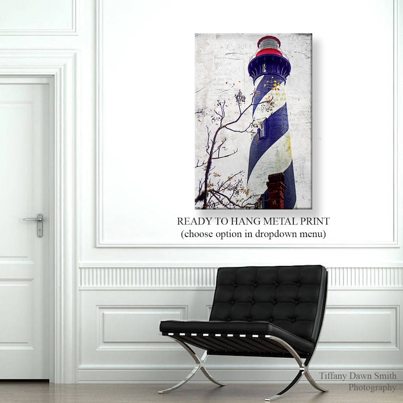 May include: Metal print of a lighthouse with blue and white stripes, a red top, and a brick base. The print has a distressed, vintage look. The text "READY TO HANG METAL PRINT" is at the bottom. A black leather chair is in the foreground.