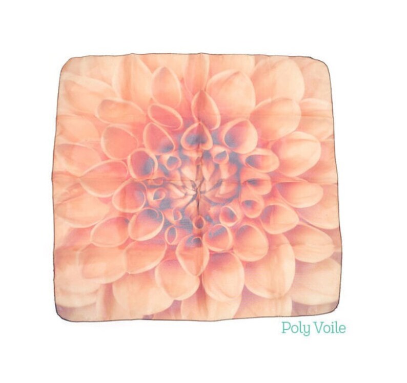 May include: A square peach-coloured silk scarf with a large, detailed floral print of a dahlia flower. The text "Poly Voile" is printed in the bottom right corner.