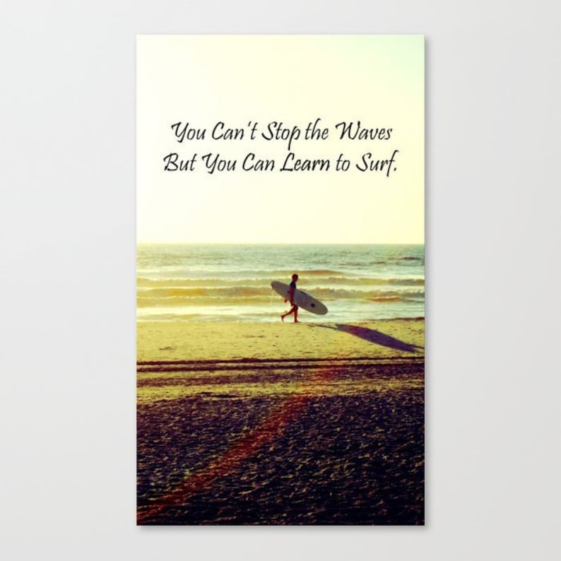K&ouml;nnte beinhalten: Leinwanddruck mit einer Strandszene, auf der eine Person ein Surfbrett tr&auml;gt. Der Text "You Can't Stop the Waves But You Can Learn to Surf" ist in eleganter Schrift &uuml;ber der Person zu sehen. Das Bild hat einen warmen, goldenen Farbton.