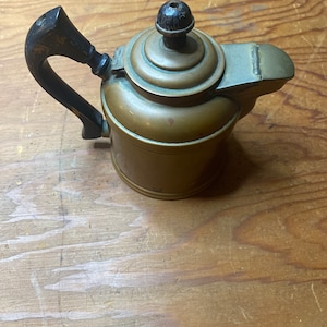 Liten koppar tekanna med träknopp och handtag med klaff över pipen