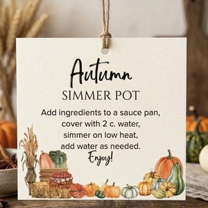 Peut inclure: Une étiquette carrée blanc cassé avec de la ficelle, portant le texte Autumn SIMMER POT et des instructions pour ajouter des ingrédients dans une casserole avec 2 c. d'eau. Le bas est orné d'une illustration aquarelle de citrouilles et de blé.
