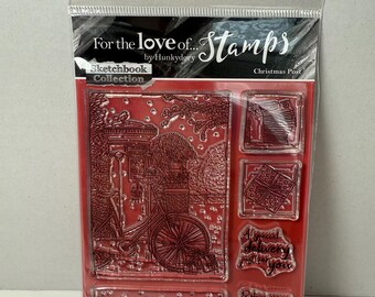May include: Clear plastic package containing a set of red rubber stamps. The stamps feature various designs, including a bicycle, a bird, and text that reads "For the love of... Stamps" and "Peace on Earth". The set is part of the "Sketchbook Collection".