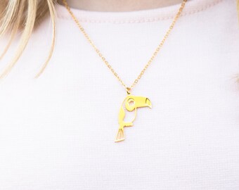 May include: A young girl wearing a pink shirt with a gold toucan pendant necklace.