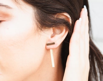 May include: Gold bar earrings with a long, thin bar hanging down from the top bar.