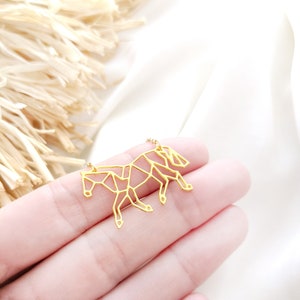 May include: A gold-toned necklace with a geometric horse pendant. The horse is made of thin metal and has a detailed, origami-like design.