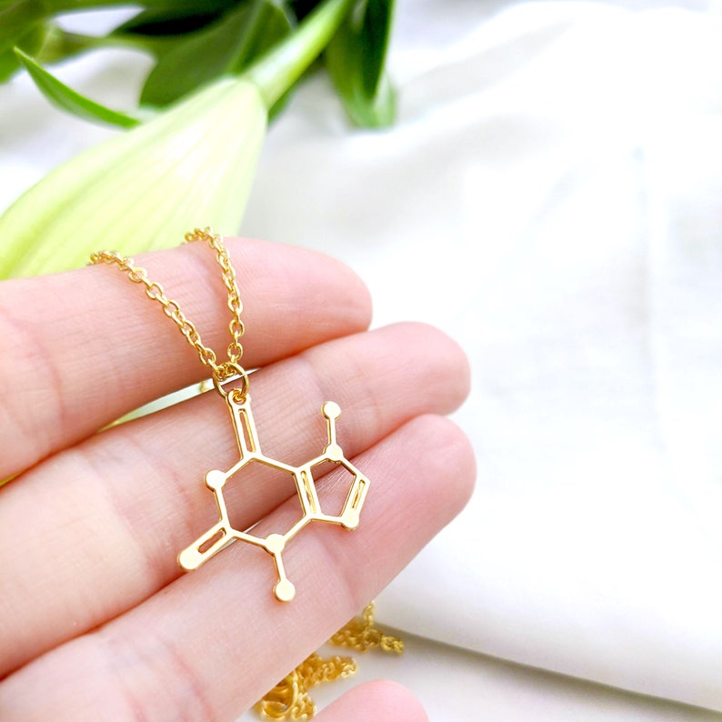 May include: A gold necklace with a pendant shaped like the chemical structure of caffeine.