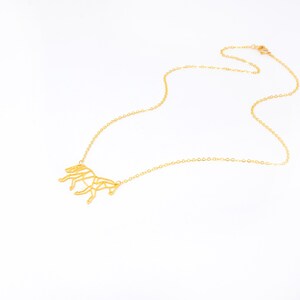 May include: A gold necklace featuring a geometric horse pendant. The chain is delicate and the pendant is detailed.