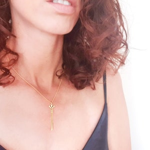 May include: A gold necklace with a sword pendant. The sword is a simple design with a pointed tip and a small cross at the top.