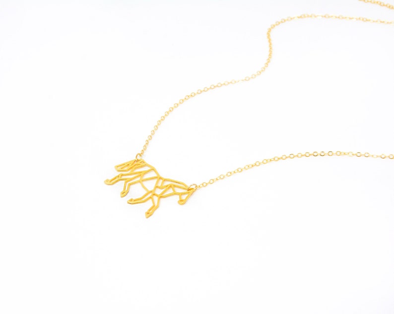 May include: A gold chain necklace with a geometric horse pendant.