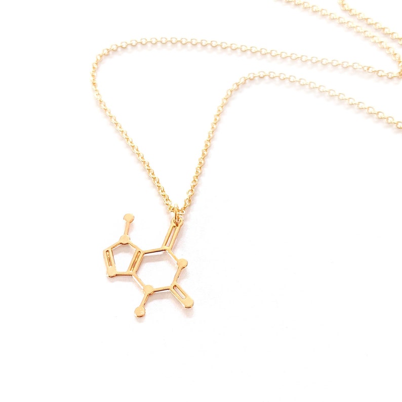 May include: A gold necklace with a pendant shaped like the chemical structure of dopamine. The necklace is made of a delicate chain.