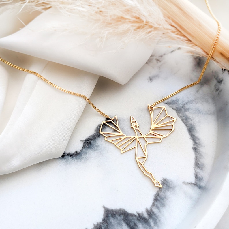Puede incluir: Un collar de oro con un colgante de drag&oacute;n geom&eacute;trico. El drag&oacute;n est&aacute; hecho de metal fino y tiene un dise&ntilde;o delicado e intrincado.