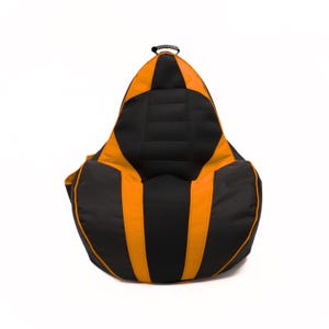 May include: A black and orange bean bag chair. The chair has a teardrop shape with a black top and sides, and orange accents. A black handle is at the top. The bean bag is designed for comfortable seating.