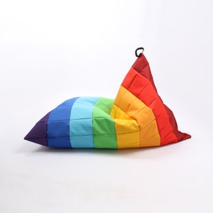 Könnte beinhalten: Ein Regenbogenfarbener Sitzsack mit Reißverschluss. Der Sitzsack ist aus gestepptem Stoff gefertigt und hat verschiedene Farben, darunter Rot, Orange, Gelb, Grün, Blau, Indigo und Violett.