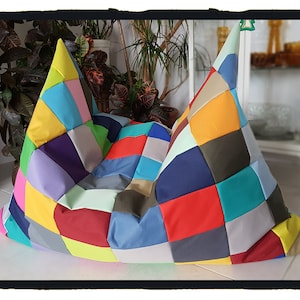 Op de afbeelding: Een kleurrijke patchwork-zitzak met verschillende kleuren, waaronder rood, blauw, geel, groen en paars.