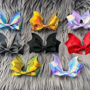 K&ouml;nnte beinhalten: Ein Set mit zehn Fledermaus-Haarspangen in verschiedenen Farben und Mustern, darunter schillernd, rot, schwarz und gold. Die Schleifen sind aus Stoff und haben eine mittlere Schleife.