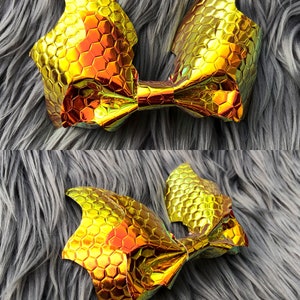 K&ouml;nnte beinhalten: Eine goldene Schleife mit einem Wabenmuster. Die Schleife ist aus einem gl&auml;nzenden, schillernden Material gefertigt.