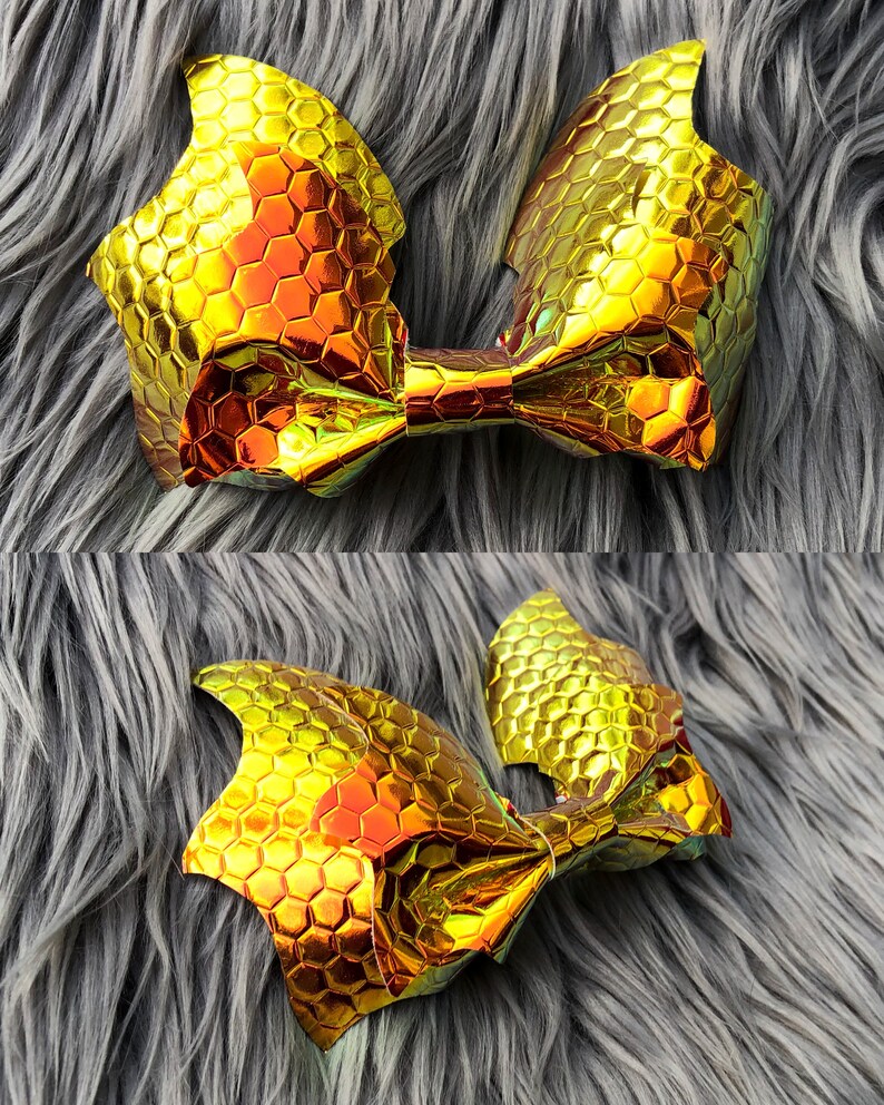 K&ouml;nnte beinhalten: Eine goldene Schleife mit einem Wabenmuster. Die Schleife ist aus einem gl&auml;nzenden, schillernden Material gefertigt.