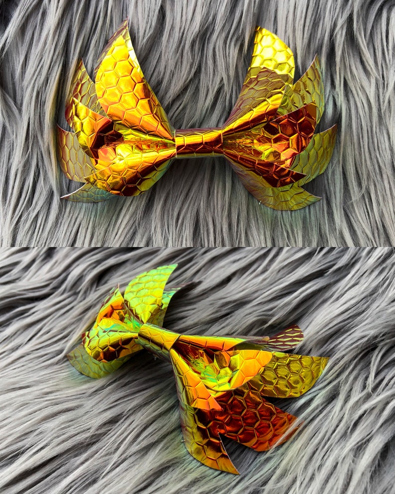 May include: A large gold bow with a honeycomb pattern. The bow is made of iridescent material and has a slightly 3D effect.