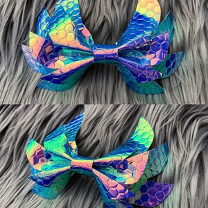 May include: A large iridescent blue and green bow with a honeycomb pattern. The bow is made of a shiny, textured material and has a pointed shape.