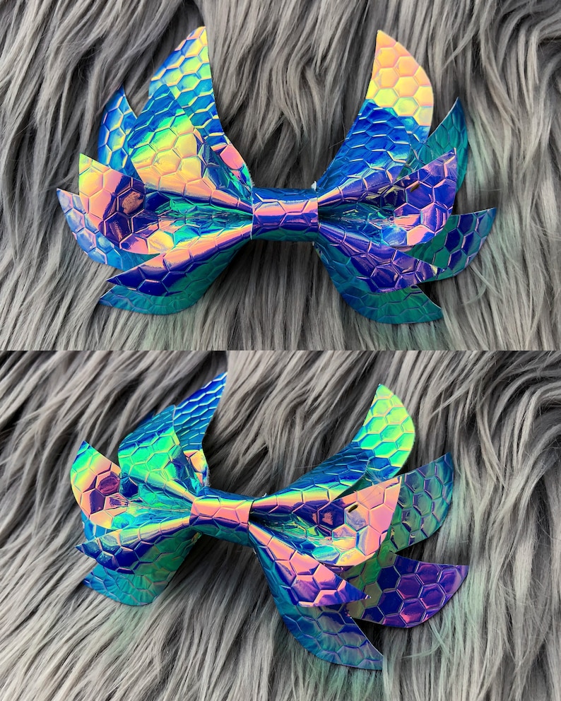 May include: A large iridescent blue and green bow with a honeycomb pattern. The bow is made of a shiny, textured material and has a pointed shape.