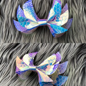 May include: A large iridescent purple and blue bow with a honeycomb pattern. The bow is made of fabric and has a pointed shape.