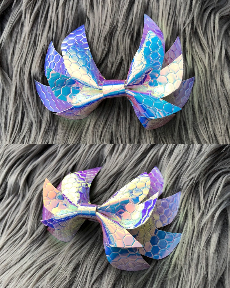 May include: A large iridescent purple and blue bow with a honeycomb pattern. The bow is made of fabric and has a pointed shape.