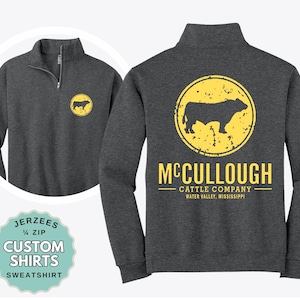 May include: A dark charcoal gray quarter-zip sweatshirt featuring a yellow circular logo with a cattle silhouette on the left chest and a larger version on the back with the text "McCULLOUGH CATTLE COMPANY WATER VALLEY, MISSISSIPPI".