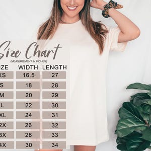 May include: A cream-colored t-shirt with a size chart overlay. The chart lists sizes XS to 4X, with width and length measurements in inches. The model is wearing the t-shirt.