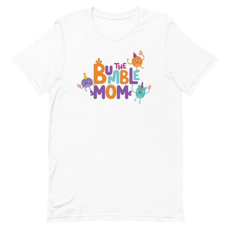 Puede incluir: Camiseta blanca con el texto "BUMBLE MOM" en naranja, morado y azul. La camiseta presenta personajes de dibujos animados con gorros de fiesta. El dise&ntilde;o est&aacute; centrado en la parte delantera de la camiseta.