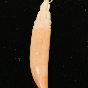 vintage dime store hand carved bone horn with sitting statue on top.