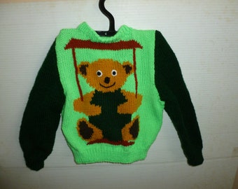 Knitted child's  jumper with baby bear on swing