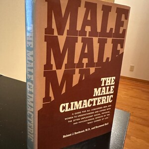 May include: A hardcover book titled "Male Male Male" in large brown letters. The book's title continues with "The Male Climacteric" in white text. The book's subtitle is a guide for men and women.
