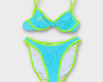 Könnte beinhalten: Ein blauer Bikini mit einem lindgrünen Saum. Das Oberteil hat ein Blumenmuster und das Unterteil ist hoch geschnitten.