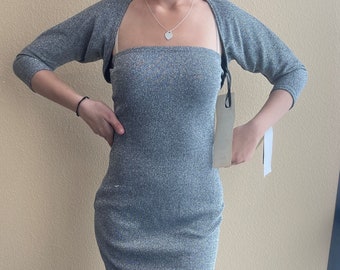 May include: A grey sparkly knit dress with a matching knit shrug. The dress is strapless and has a fitted silhouette. The shrug has 3/4 sleeves.