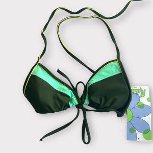 Puede incluir: Un top de bikini verde oscuro con ribetes verde claro y amarillo. El top tiene tirantes ajustables y lazos en la parte posterior. La etiqueta dice "Dream"