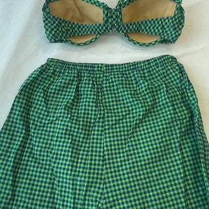 May include: A two-piece swimsuit set in a green and navy blue gingham pattern. The top is a halter-style bikini with a tie closure. The matching shorts have an elastic waistband. The swimsuit is made of a lightweight fabric.