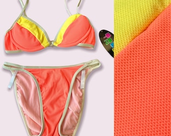 May include: A coral and yellow bikini with a textured fabric. The top has a halter style with adjustable straps and a clasp closure in the front. The bottom is a high-cut style with a low rise.