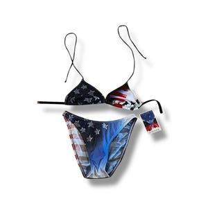 May include: A two-piece bikini set featuring a patriotic design. The top is a triangle style with black straps, and the bottoms are a classic cut. The fabric showcases a pattern of stars, stripes, and the colors red, white, and blue.