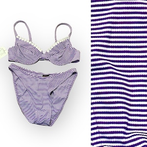 Puede incluir: Bikini a rayas moradas y blancas con un ribete blanco en la parte superior. El bikini está hecho de una tela acanalada.
