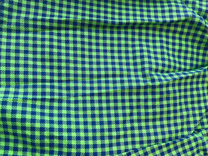 May include: A fabric with a repeating checkered pattern. The pattern features a vibrant green and navy blue color scheme. The fabric is likely used for clothing or home decor.