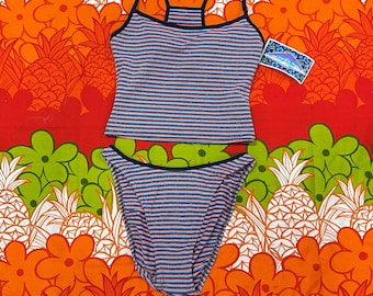 May include: A two-piece swimsuit set with a striped pattern in blue, orange, and white. The top is a tankini style with thin straps and a dark blue trim. The bottoms are a classic bikini cut. The set is displayed on a colorful background.
