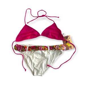 May include: A pink bikini top with a white bottom. The bottom has a colorful floral print around the waistband.