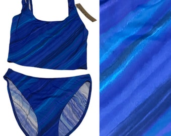 Può includere: Costume da bagno a righe blu e viola con top a scollo rotondo e slip a vita alta.
