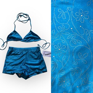 Puede incluir: Un conjunto de bikini azul turquesa con top triangular con lazos y shorts a juego. La tela tiene un brillo sutil. Un primer plano muestra una tela azul turquesa con un estampado floral.