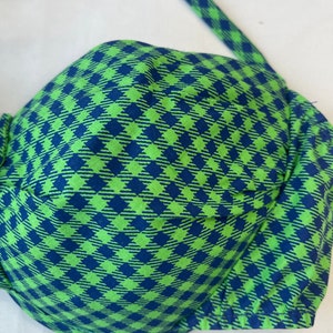 May include: A green and blue checkered bikini top. The top features a classic bra-style design with adjustable straps. The fabric has a repeating diamond pattern in shades of green and blue. The bikini top is made of a soft, lightweight material.